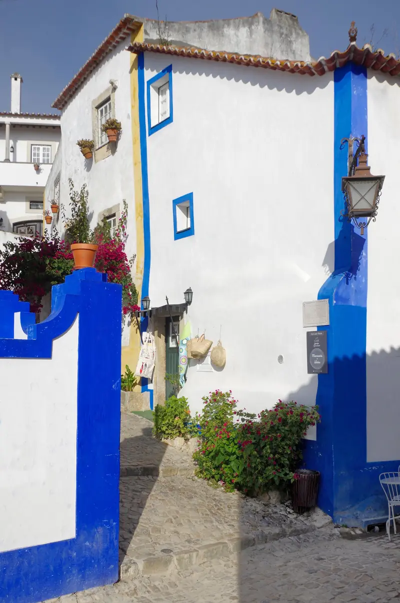 Rua Direita de Óbidos com casas brancas de barras azuis e amarelas